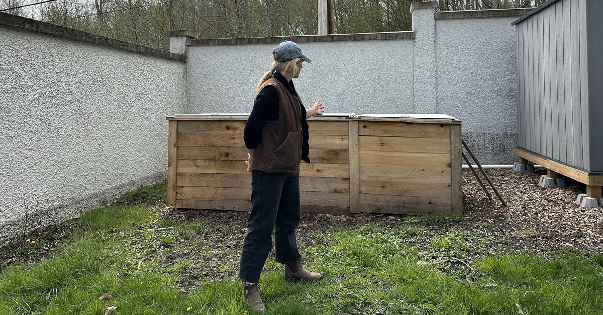 Woman standing in front of a large cedar compost box.